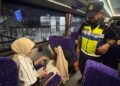 SEORANG anggota JPJ Pulau Pinang melihat seorang penumpang bas ekspres memakai tali pinggang keledar dengan cara yang betul ketika Operasi Khas Pemakaian Tali Pinggang Keledar bagi Bas Ekspres dan Bas Persiaran di Penang Sentral, Butterworth, Pulau Pinang malam tadi.-UTUSAN/ISWAN SHAFIQ ISA