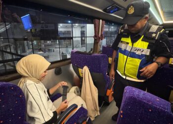 SEORANG anggota JPJ Pulau Pinang melihat seorang penumpang bas ekspres memakai tali pinggang keledar dengan cara yang betul ketika Operasi Khas Pemakaian Tali Pinggang Keledar bagi Bas Ekspres dan Bas Persiaran di Penang Sentral, Butterworth, Pulau Pinang malam tadi.-UTUSAN/ISWAN SHAFIQ ISA