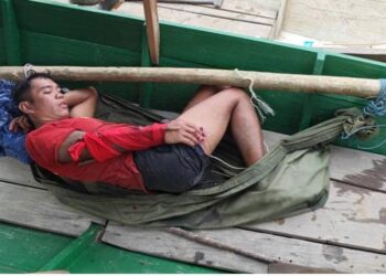 Dennis terbaring di dalam perahu sementara menunggu bantuan daripada penduduk kampung.