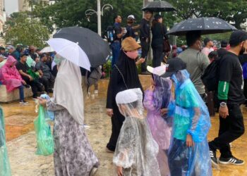PESERTA-peserta Himpunan Turun Anwar memakai baju hujan untuk terus berhimpun di Dataran Merdeka, Kuala Lumpur.