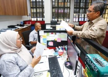 MOHAMAD Yusri Bakir berbincang dengan pegawainya mengenai aduan rakyat yang diterima di pejabatnya di Tapah.
