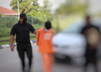TERTUDUH diiringi anggota polis semasa menghadiri prosiding perbicaraan di Mahkmah Seysen Kota Bharu, Kelantan. - UTUSAN/ROSALWANI CHE SOH