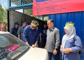 AZMAN Ismail (dua dari kanan) melihat Mohd. Syahbuddin Hashim (tiga dari kanan) mengisi minyak petrol di pos bekalan bahan api di Pos Brooke, Gua Musang, Kelantan, hari ini.- UTUSAN/AIMUNI TUAN LAH
