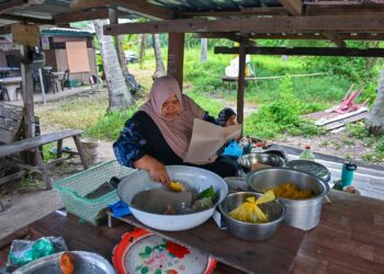 Hawa Muhammad membungkus nasi dagang untuk dijual kepada pelanggan yang dating ke gerainya di Kampung Ladang. – UTUSAN/PUQTRA HAIRRY