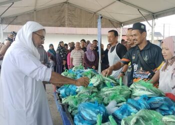 SYED Abu Hussin Hafiz Syed Abdul Fasal (kiri) mengagihkan ikan percuma kepada penduduk di Pusat Khidmat beliau di Bukit Gantang hari ini. - UTUSAN/WAT KAMAL ABAS