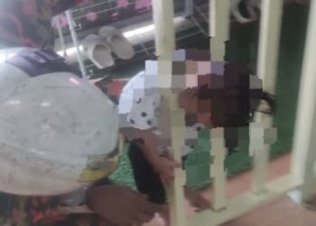SEORANG anggota bomba membantu mengeluarkan kepala kanak-kanak perempuan yang tersepit di celah besi penghadang sebuah taska di Taman Jawi Indah, Nibong Tebal, Pulau Pinang.-GAMBAR/JBPM PULAU PINANG