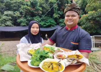 NASIRUDDIN Mohd dan Nur Jannah Anuar menunjukkan antara hidangan di Warung Sungai Berakir di Kampung Tapah, Hulu Terengganu. – MINGGUAN/NOOR HAYATI MAMAT