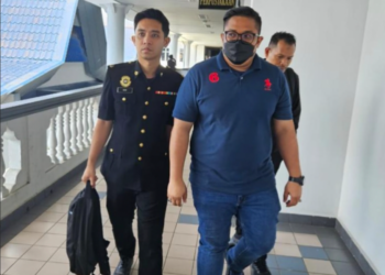 TERTUDUH diiringi pegawai SPRM selepas mengaku bersalah menerima suapan di Mahkamah Sesyen Ayer Keroh, Melaka hari ini.