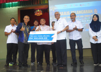Rais Yasin menyaksikan Ketua Perniagaan Global TNB, Datuk Azmi Md. Yusof menyampaikan penajaan RM100,000 kepada Pengetua, Johan Othman di SMK Tinggi Melaka. UTUSAN/AMRAN MULUP