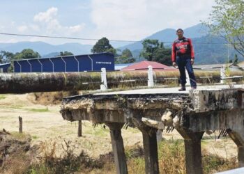 AHMAD Dauh menunjukkan jambatan yang runtuh akibat kejadian kepala air pada Ogos tahun lalu di Kampung Lintah Piong, Slim Village dekat Tanjung Malim. - UTUSAN/AIN SAFRE BIDIN