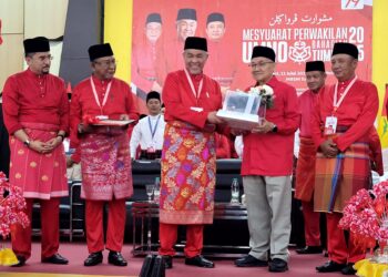ASYRAF Wajdi Dusuki (kiri) menyaksikan Pengerusi Majlis Ulama UMNO, Datuk Dusuki Ahmad (dua dari kanan) yang juga bapanya menerima Anugerah Tokoh Melayu UMNO dari Ahmad Zahid Hamidi pada Majlis Perasmian Mesyuarat Perwakilan UMNO Bahagian Tumpat, Kelantan hari ini. - UTUSAN/MUSTAQIM MOHAMED