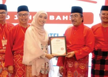 JOHARI Abdul Ghani menyampaikan sijil Sekolah Politik UMNO kepada seorang perwakilan Puteri UMNO sempena Mesyuarat Perwakilan UMNO Bahagian Johor Bahru, semalam. - UTUSAN/RAJA JAAFAR ALI