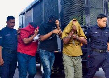 KESEMUA tertuduh diiringi anggota polis selepas dihadapkan di Mahkamah Majistret Jasin hari ini atas pertuduhan membunuh seorang lelaki pada 27 Julai lalu. - UTUSAN/ARIF HAMIZAN MISKON