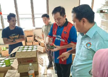 TAN Eng Meng (tengah) melihat makanan dalam tin import telah tamat tempoh yang diproses oleh sebuah kilang hingga menyebabkan bau busuk di Kawasan Perindustrian Sentral Pekan Nanas di Pontian, hari ini.