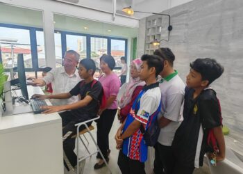 KHOO Poay Tiong (kiri) bersama pelajar yang menggunakan kemudahan di Perpustakaan Digital Parlimen Kota Melaka sempena majlis peluncurannya di Kampung Tujuh, Jalan Gajah Berang, Melaka. - UTUSAN/AMRAN ALI