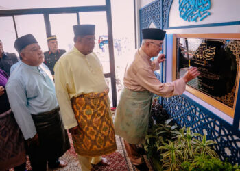 MOHD. Ali Mohd. Rustam menandatangani plak sambil diperhatikan Ab. Rauf Yusoh pada perasmian Masjid Al-Muhtadi di Ramuan China Besar, Melaka. - UTUSAN/AMRAN MULUP