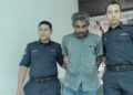 TERTUDUH diiringi anggota polis ketika dihadapkan ke Mahkamah Majistret Alor Gajah, Melaka atas pertuduhan mencuri buah kelapa sawit seberat 540 kilogram. - UTUSAN/MUHAMMAD SHAHIZAM TAZALI