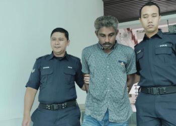 TERTUDUH diiringi anggota polis ketika dihadapkan ke Mahkamah Majistret Alor Gajah, Melaka atas pertuduhan mencuri buah kelapa sawit seberat 540 kilogram. - UTUSAN/MUHAMMAD SHAHIZAM TAZALI