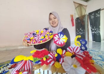 SITI Nur Natrah Yatimi Mohd. Azmi menunjukkan bunga raya yang dihasilkan daripada dawai berbulu berwarna-warni di Kampung Gong Duek, Besut, Terengganu. – UTUSAN/WAN ZURATIKAH IFFAH WAN ZULKIFLI