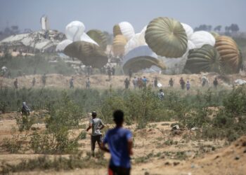 PENDUDUK Palestin berpusu-pusu ke lokasi jatuhan pakej bantuan yang dihantar melalui udara di kawasan Nuseirat, tengah Semenanjung Gaza. – AFP