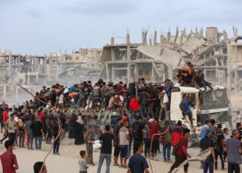 PENDUDUK Palestin memanjat trak bantuan kemanusiaan yang memasuki Gaza di Beit Laha pada 29 Julai lalu. – AFP