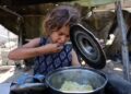 SEORANG kanak-kanak Palestin menjamah nasi yang dimasak dengan jarinya selepas menerima hidangan dari dapur amal di Gaza City, kelmarin.- AFP