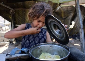 SEORANG kanak-kanak Palestin menjamah nasi yang dimasak dengan jarinya selepas menerima hidangan dari dapur amal di Gaza City.- AFP
