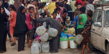 PENDUDUK Palestin beratur untuk mendapatkan bekalan air minuman di bawah terik matahari di kawasan Al-Mawasi di Khan Younis, selatan Semenanjung Gaza.-AFP