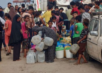 PENDUDUK Palestin beratur untuk mendapatkan bekalan air minuman di bawah terik matahari di kawasan Al-Mawasi di Khan Younis, selatan Semenanjung Gaza.-AFP