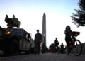 PELANCONG berbasikal melalui kenderaan Pengawal Kebangsaan berhampiran Monumen Washington pada Selasa lalu. – AGENSI