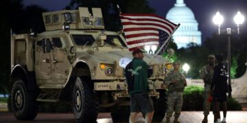SEORANG penunjuk perasaan mengibarkan bendera kebangsaan AS terbalik ketika anggota Pengawal Kebangsaan berkawal di sebelah kenderaan perisai di luar Stesen Union, Washington, kelmarin.- AFP