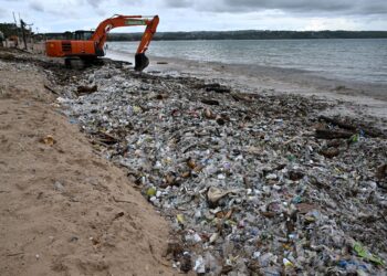 PEKERJA menggunakan jentera berat untuk membersihkan sampah-sarap yang memenuhi pesisir pantai di Kedonganan Badung, Bali. – AFP