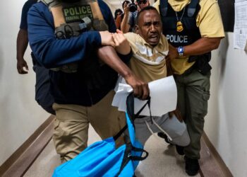 ANGGOTA penguat kuasa menahan seorang pendatang lelaki di New York, Amerika Syarikat. - AFP