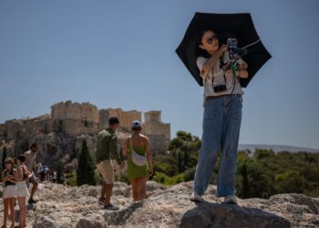 SEORANG pelancong merakam gambar berhampiran tapak monumen Acropolis ketika gelombang haba melanda di Athens, Greece. – AFP