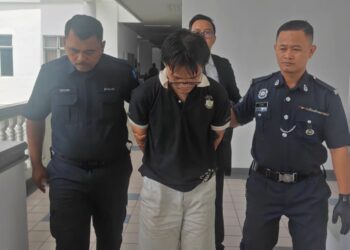 TERTUDUH diiringi anggota polis keluar dari Mahkamah Majistret Ayer Keroh selepas mengaku tidak bersalah atas pertuduhan mencuri pelbagai barangan daripada sebuah pasar Mini di Batu Berendam, pada 10 Ogos lalu. - UTUSAN /AMRAN ALI.