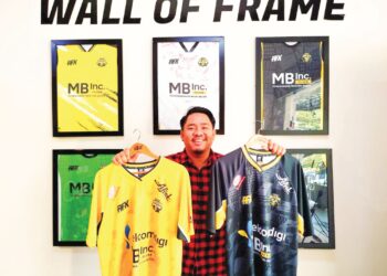 ZARUL Iskandar menunjukkan jersi yang dihasilkan syarikatnya di Kuala Kangsar. – UTUSAN/FADZIL ZAINOL