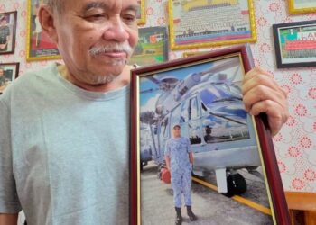 MOHD. Termizi Abdul Ghani melihat gambar arwah anaknya, Pegawai Waran II Mohd. Shahrizan di rumahnya di Batu 10, Lekir, Lumut, Perak semalam.