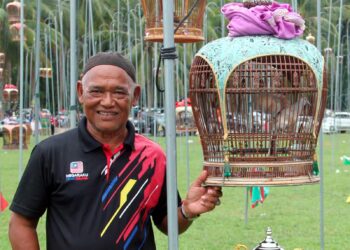 ISMAIL Hassan bersama burung merbuk ‘Madu Tiga’ miliknya yang muncul juara kategori utama Pertandingan Suara Burung Ketitir Nasional Selatan Thai, Narathiwat, Thailand. – UTUSAN/RAZALI ZAKARIA.