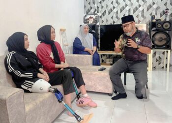 DR. Asmadi Abdul Rahman menyampaikan sumbangan kaki palsu kepada Nik Haziera Safiyya Nik Husmadi (kiri) dan Nik Haznita Safiyya  sambil diperhatikan Noriah Adjun di rumah mereka di Lebak, Temerloh, Pahang semalam. – UTUSAN/ DIANA SURYA ABD. WAHAB