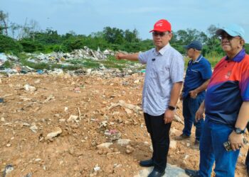 SUHAIZAN Kayat (kiri) menunjukkan tanah lapang yang dijadikan tapak pembuangan sampah haram di Kampung Tuah Jaya berhampiran Taman Perling, Johor Bahru.