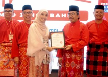 JOHARI Abdul Ghani menyampaikan sijil Sekolah Politik UMNO kepada seorang perwakilan Puteri UMNO sempena Mesyuarat Perwakilan UMNO Bahagian Johor Bahru, hari ini. - UTUSAN/RAJA JAAFAR ALI