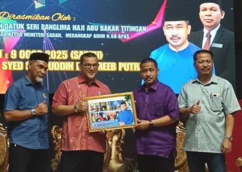 NIZAM Abu Bakar Titingan (tengah) menerima cenderamata daripada Dr. Rabe Juhari selepas merasmikan Mesyuarat Agung Persatuan Ibu Bapa dan Guru (PIBG) Kolej Tingkatan Enam Pra-Universiti Tawau, hari ini. - UTUSAN/BESSE AISYAH
