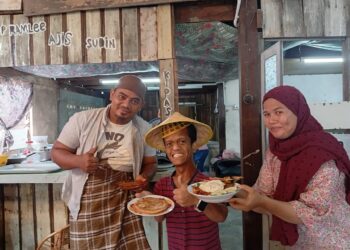 WAN Ahmad Faizul Ahmad Azhar (kiri) Nur Shela Abdullah (kanan) menunjukkan Nasi Goreng Ikan Klasik dan Lempeng Nyior yang dijual di Kopi Kayu Klasik Pak Belalang di Kampung Pak Tuyu, Kuala Nerus, Terengganu. – UTUSAN/ERMA YUSNIDA JUSOH
