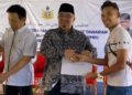 MOHAMED Fadzli Hassan (dua kiri) menyerahkan Surat Tawaran Rumah Mesra Rakyat (RMR) di Kampung Banggol Kemian, Machang, Kelantan hari ini-UTUSAN/YATIMIN ABDULLAH.