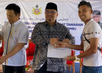 MOHAMED Fadzli Hassan (dua kiri) menyerahkan Surat Tawaran Rumah Mesra Rakyat (RMR) di Kampung Banggol Kemian, Machang, Kelantan hari ini-UTUSAN/YATIMIN ABDULLAH.