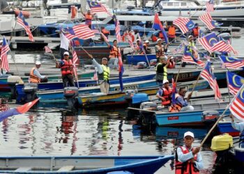 SEBAHAGIAN bot nelayan dihiasi dengan Jalur Gemilang bersiap sedia untuk berarak sejauh tiga kilometer bermula di jeti Marina Bay, Puteri Harbour sempena menyambut Bulan Kebangsaan di Iskandar Puteri, Johor. - UTUSAN/RAJA JAAFAR ALI