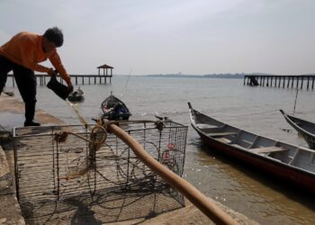 SEORANG nelayan di Pengkalan Kampung Telok, Pasir Panjang, Port Dickson hari ini membersihkan tangguk kerangnya untuk disimpan selepas larangan menuai kerang-kerangan di perairan Port Dickson dikeluarkan hari ini.--UTUSAN/MOHD SHAHJEHAN MAAMIN.