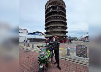 Dzulkaranaen Adanan tiba di Menara Condong Teluk Intan, Perak kelmarin bersama skuter dihiasi Jalur Gemilang dari Lanchang, Pahang ke beberapa buah negeri. – UTUSAN/AIN SAFRE BIDIN
