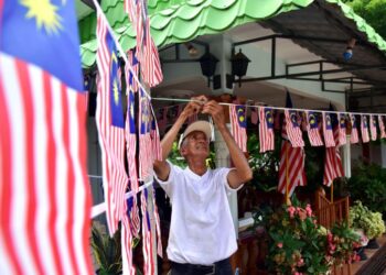 ABDUL Raship Khalil memasang Jalur Gemilang di sekitar rumahnya sempena sambutan Hari Kemerdekaan di Kampung Permatang Duyong, Melaka, semalam. - UTUSAN/ARIF HAMIZAN MISKON