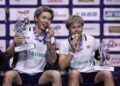 Chen Tang Jie (kiri) dan Toh Ee Wei memegang trofi mereka sambil menggigit pingat emas mereka ketika mereka meraikan di atas podium selepas menewaskan pasangan China, Jiang Zhen Bang-Wei Ya Xin dalam perlawanan akhir beregu campuran di Kejohanan Badminton Dunia di Arena Adidas, Paris hari ini. - AFP